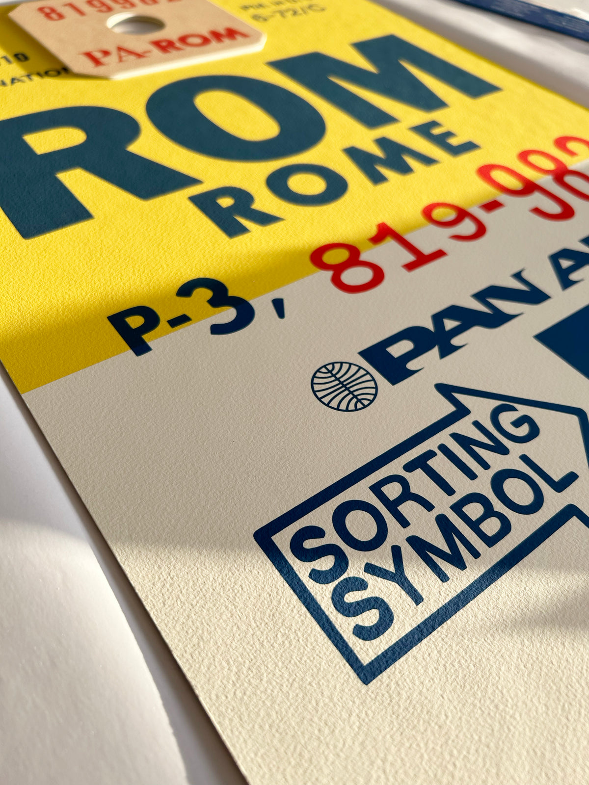 Limited-edition archival print of a Pan Am “Rome” luggage tag by Ella Freire, inspired by the original 1960s design, supersized in two framed sizes, float-mounted to enhance its three-dimensional effect; officially licensed by Pan Am with signed certificate included.